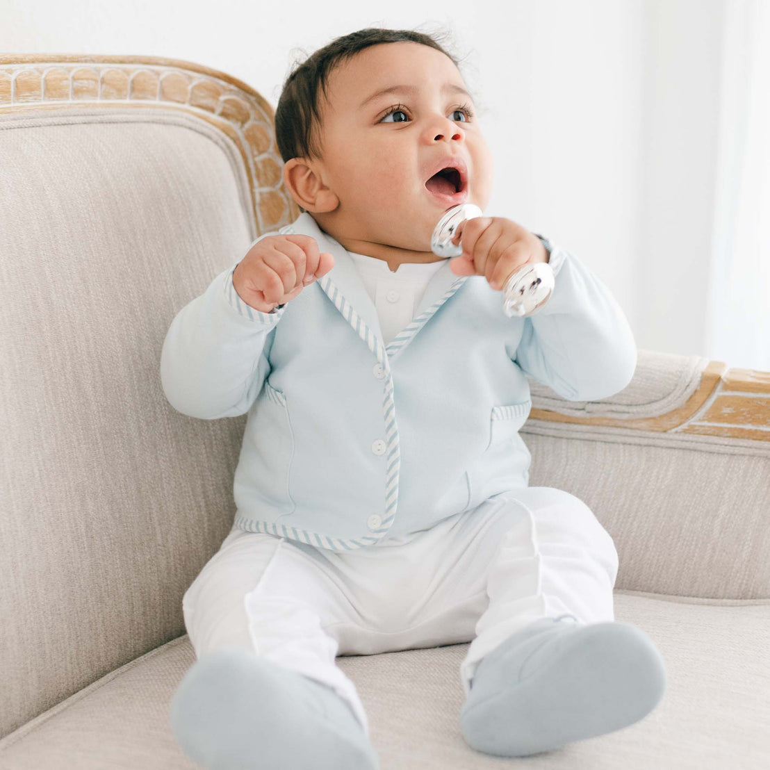 Baby boy sitting on a couch and wearing the Theodore 3-Piece Suit in blue.