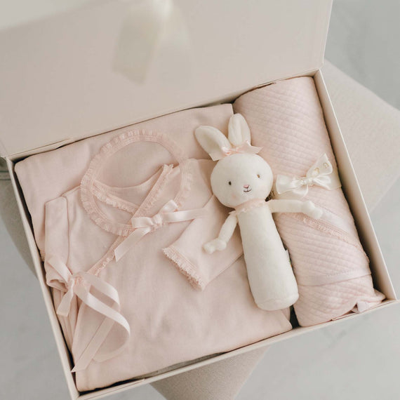 A gift box containing the Ava Newborn Gift Set, including the Ava Newborn Layette, Ava Headband, a plush Bunny Chime, and an Ava Personalized Blanket.