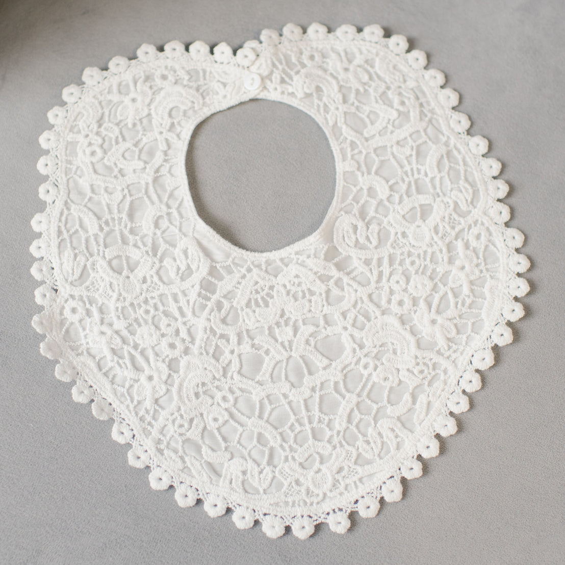 A white Grace Lace Bib collar with intricate floral patterns and scalloped edges displayed on a grey background.