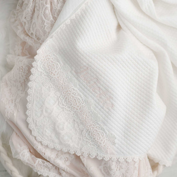 Close-up of a delicate white fabric with textured patterns and lace detailing, featuring an embroidered word "Juliette" in cursive script. This handcrafted piece showcases the upscale craftsmanship.