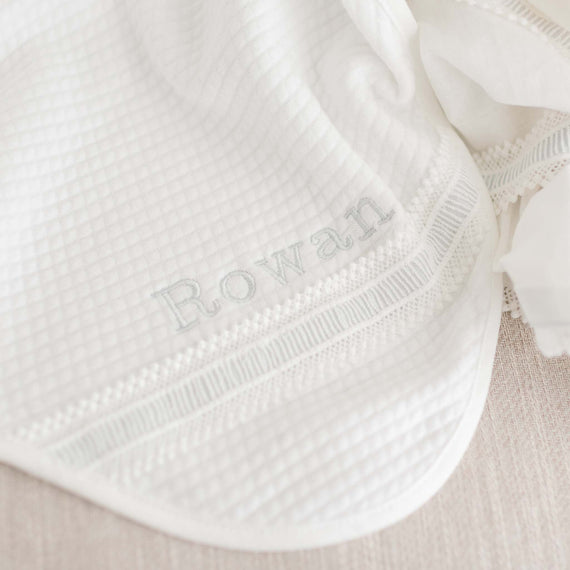 Close up detail of the embroidered name on a personalized baptism blanket. 
