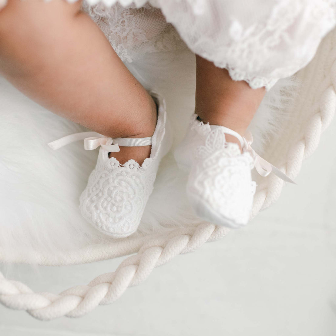 Close-up of a baby's feet in Juliette Baby Shoes, resting on a soft, furry white blanket with luxury handcrafted braided rope encircling the blanket.