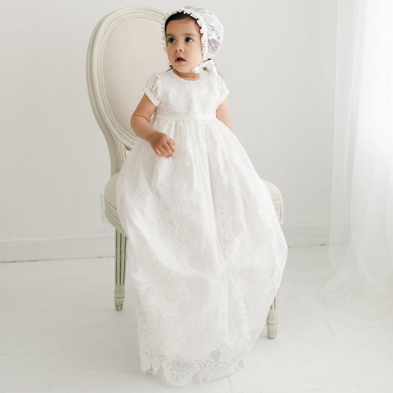 Baby girl wearing the ivory Victoria Puff Sleeve Christening Gown and Bonnet. The gown is made with ivory embroidered lace over an ivory silk Dupioni lining. 