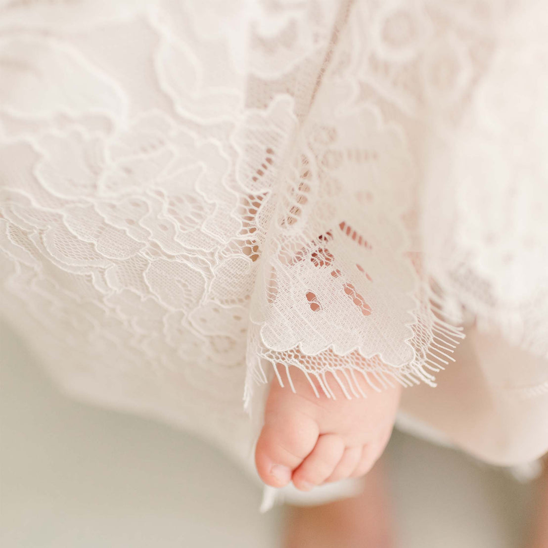 Detail of the pink Victoria Puff Sleeve Christening Dress showcasing the embroidered ivory lace on the skirt.