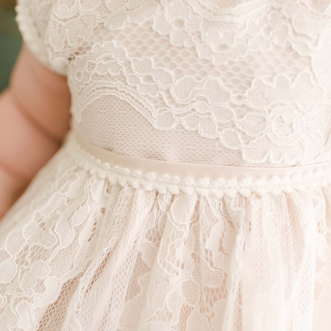 Detail of the pink Victoria Puff Sleeve Christening Dress showcasing the pink silk Dupioni lining under the embroidered ivory lace.