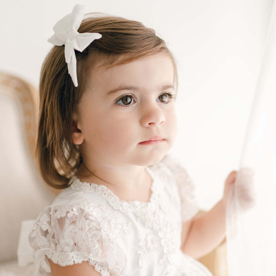 Baby girl wearing Penelope silk bow in her christening dress.
