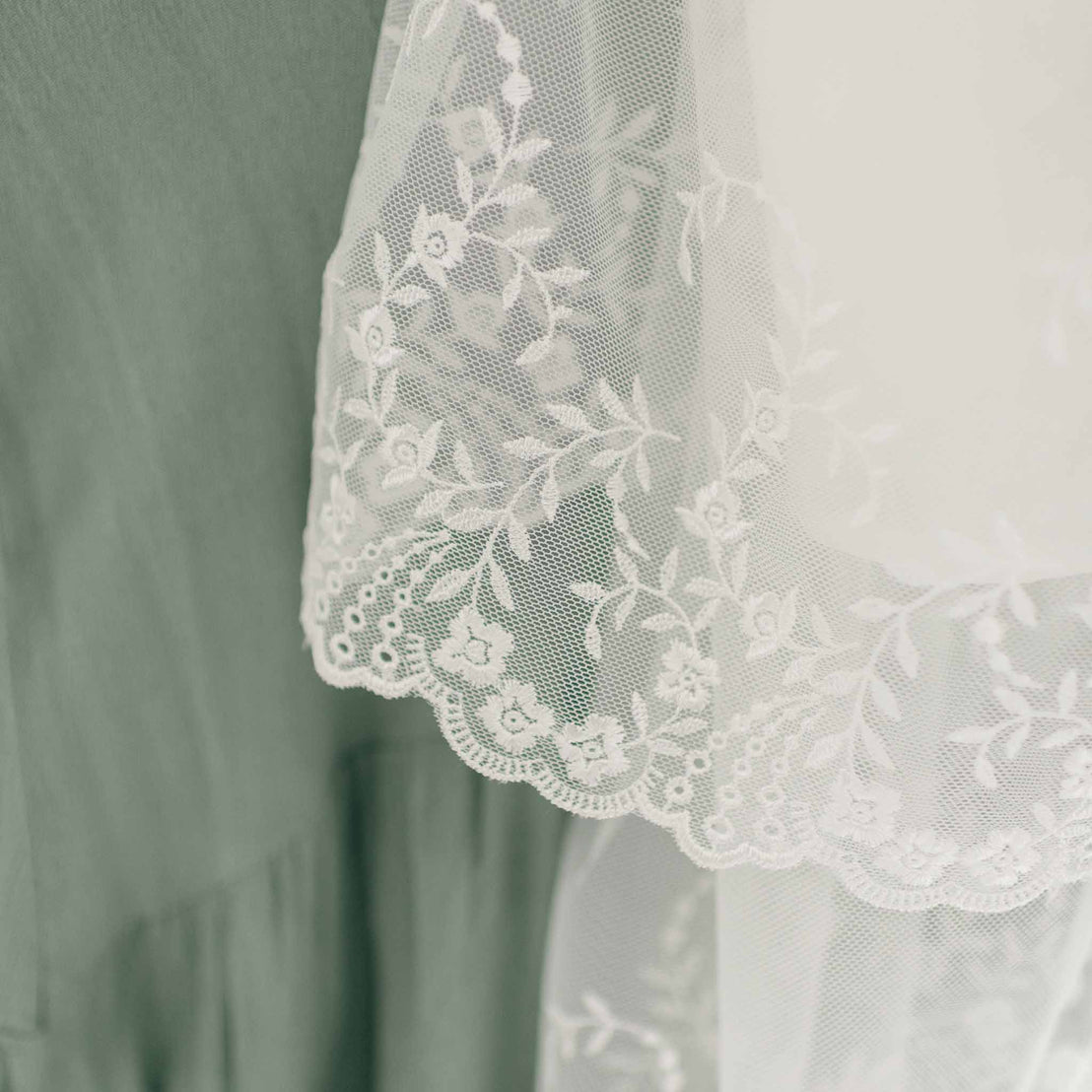 A close-up image of the lace on the Ella Christening Gown's skirt. The skirt features intricate floral embroidered netting lace details.