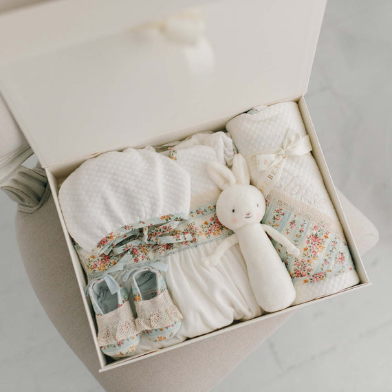 The "Sky Blue" Eloise Newborn Gift Set in the gift box, including the Layette Gown Bonnet, Booties, Bunny Chime, and Blanket.