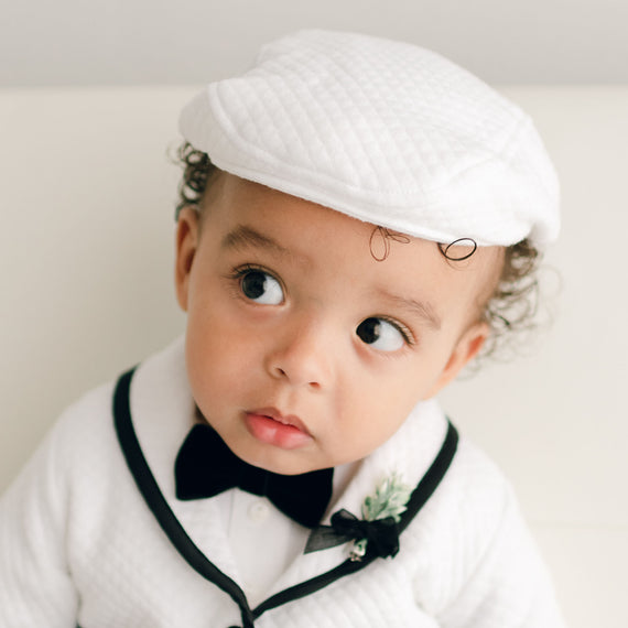 Baby boy wearing the white James Newsboy Cap made from 100% White Quilted Cotton with a soft elastic back. 
