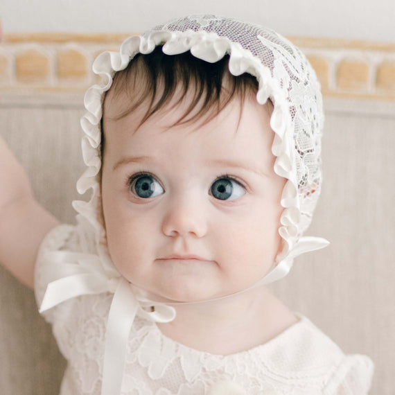 Baby girl smiling and wearing the Victoria Lace Christening Bonnet.