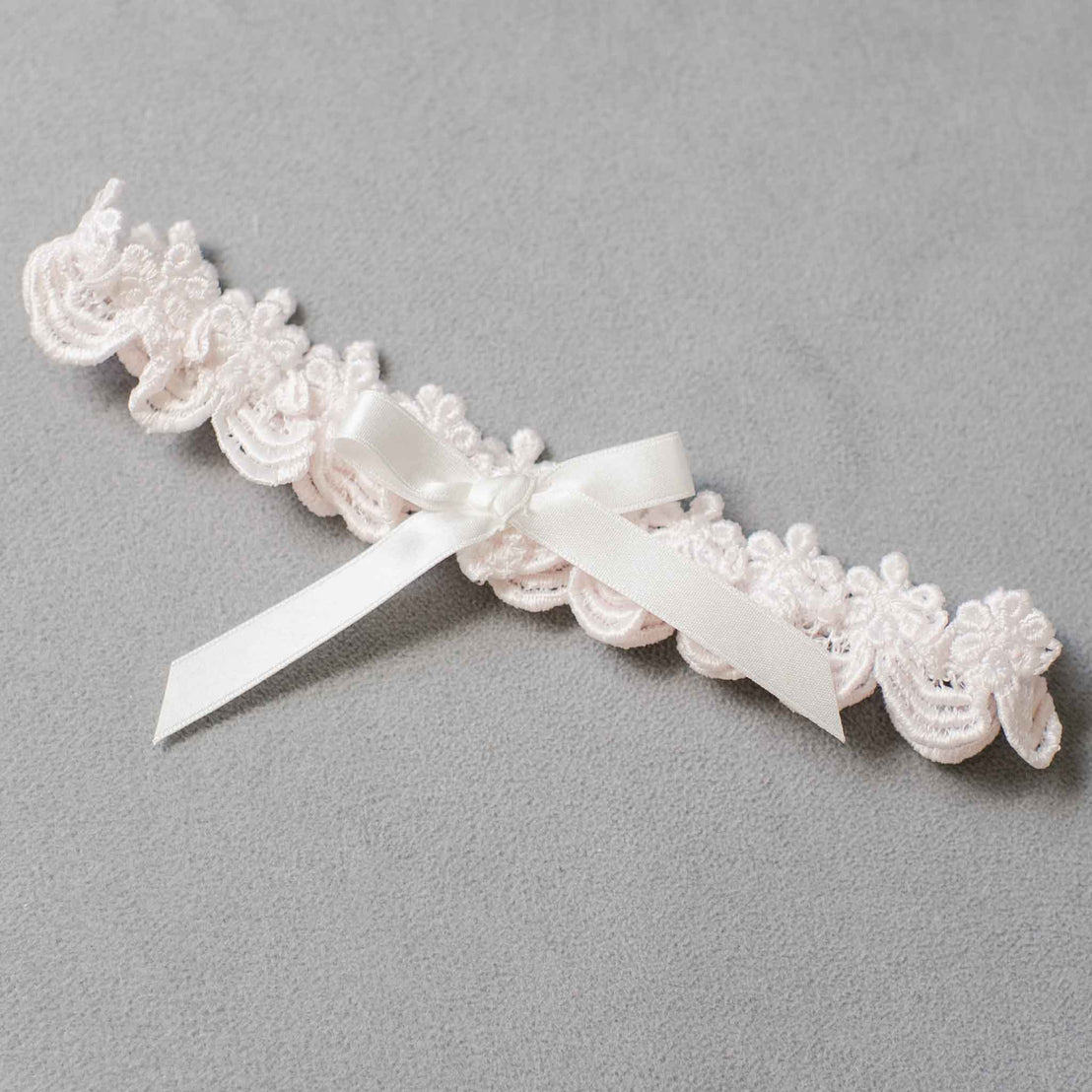 An elegant, upscale Joli  Headband with a silky ribbon bow in the center, displayed on a light gray background.