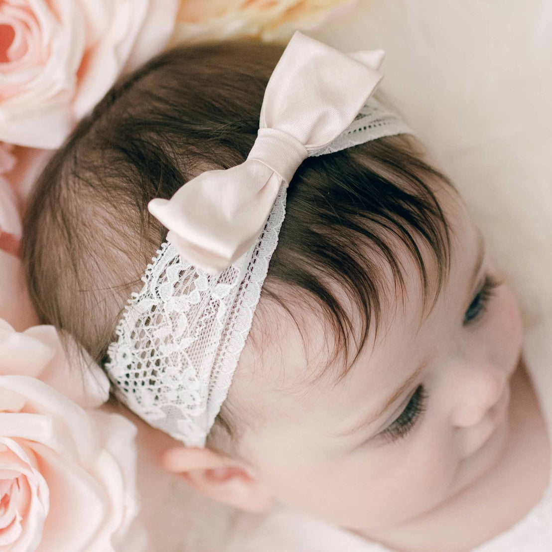 Top down view of a baby girl's head wearing the Lace Silk Bow Headband, part of the Baby Beau & Belle Victoria Collection