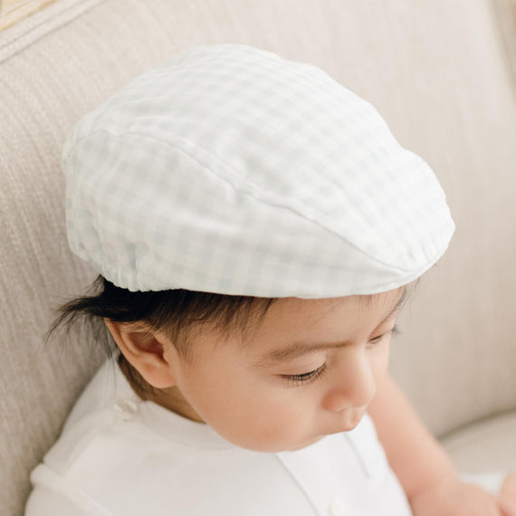 Close-up of a toddler wearing an Ian Checked Newsboy Cap, focusing on the side profile with a gentle expression and partly closed eyes. The background is soft and neutral.