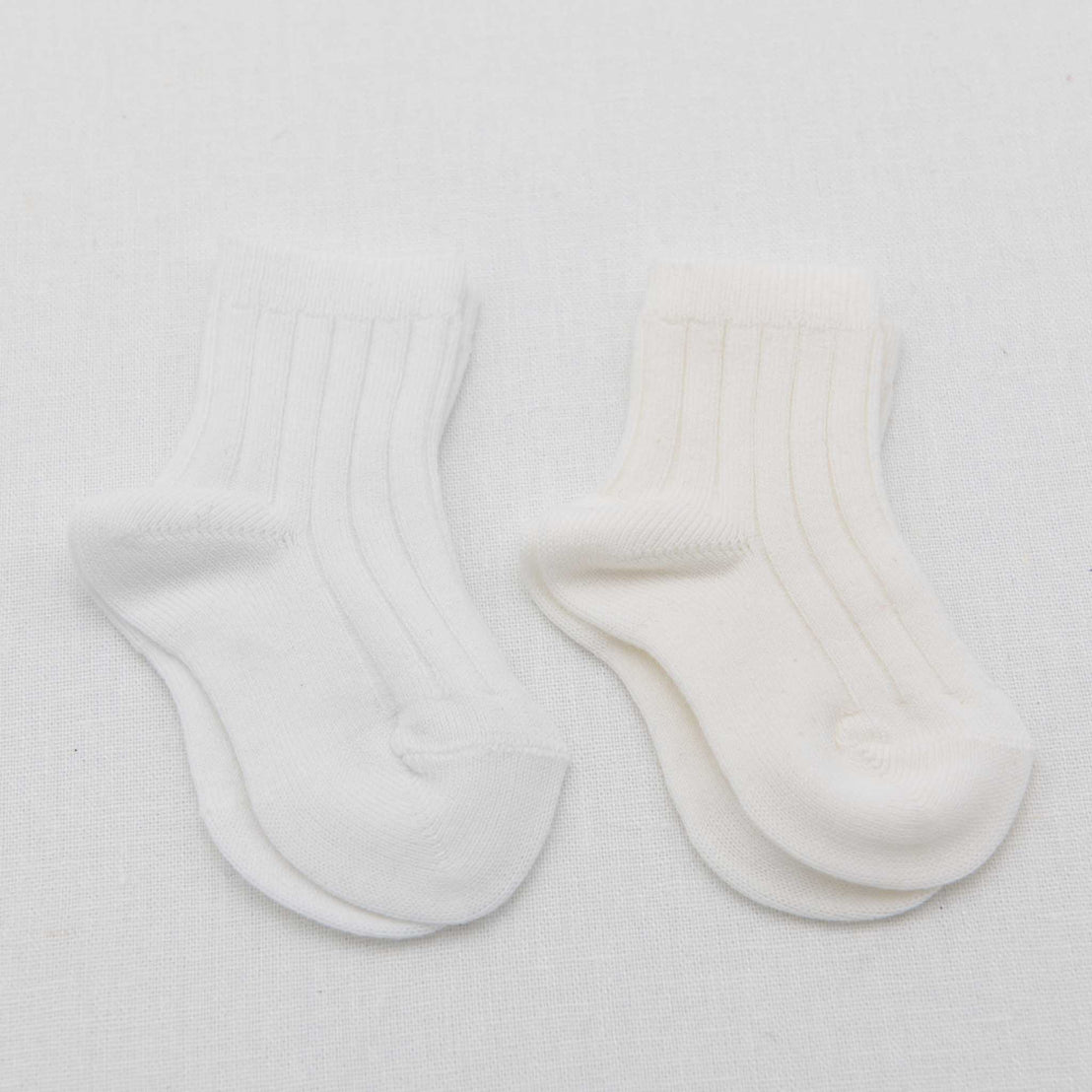 A pair of white vintage Ribbed Socks with ribbed cuffs laid flat on a white textured background.