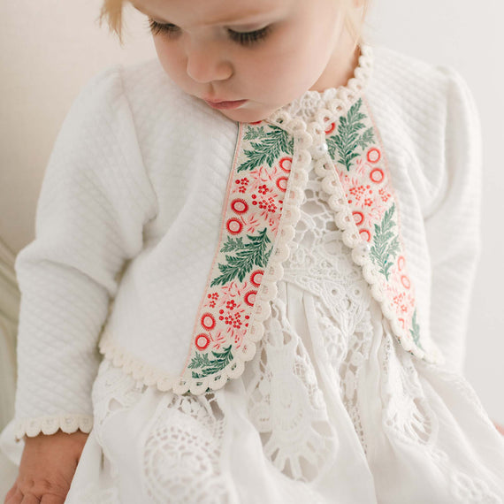 Close-up of a toddler in a Noelle Quilted Cotton Sweater with an intricate floral and lace collar, focusing on the detailed pattern and delicate fabric.