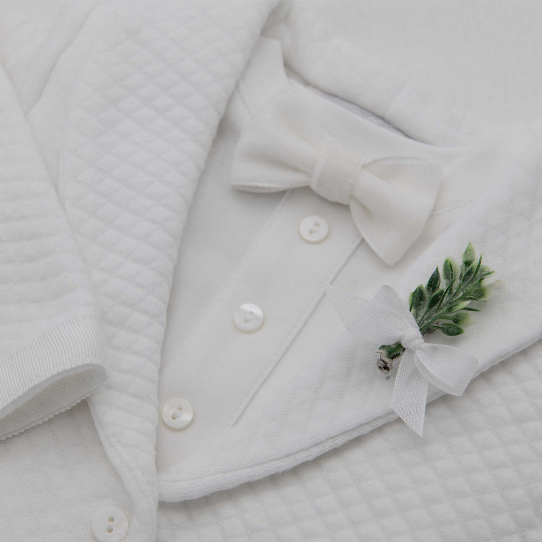 Flat lay photo of the White Velvet Bow Tie and Boutonniere that is attached to his suit
