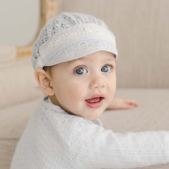 Baby boy wearing the Harrison Blue Knit Hat with the Blue Knit Sweater. The knit is detailed with soft blue linen/cotton blend edging and ivory Venice lace