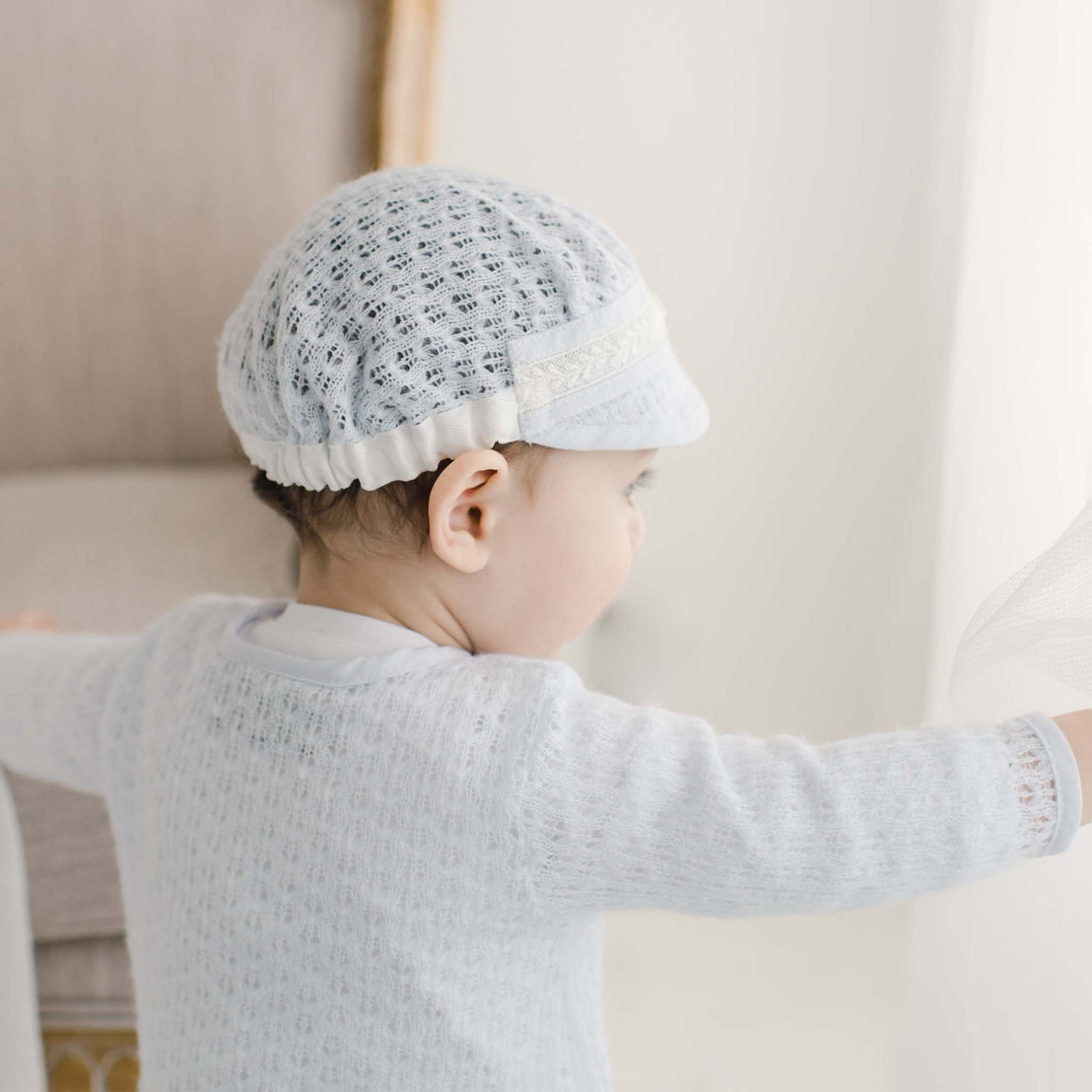Photo of baby boy featuring the back of the Harrison Blue Knit Hat. On the back is the soft elastic band that gathers in back and stretches to ensure a snug fit