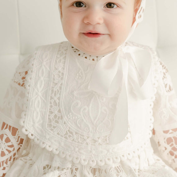 The cotton detailed Adeline bib on baby girl with red hair.