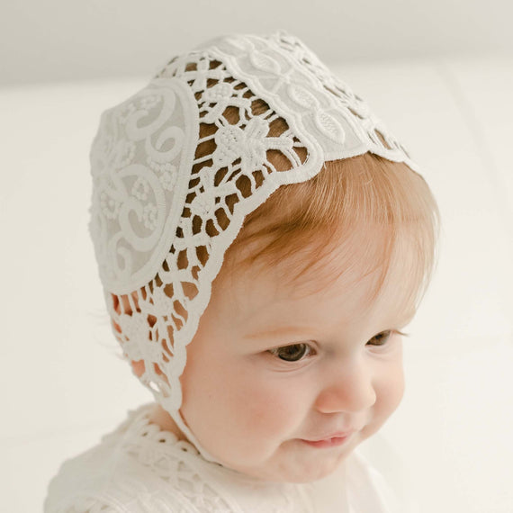 Baby girl with red hair wearing the Adeline lace christening bonnet. 