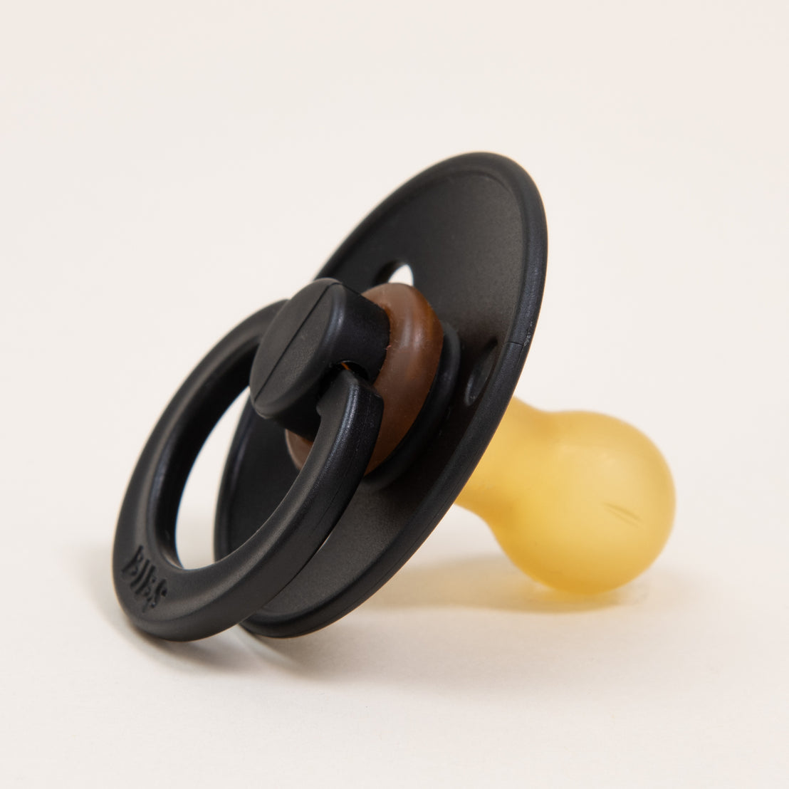 A close-up image of a Bibs Pacifier in Black with a translucent yellow nipple, placed against a plain light background.