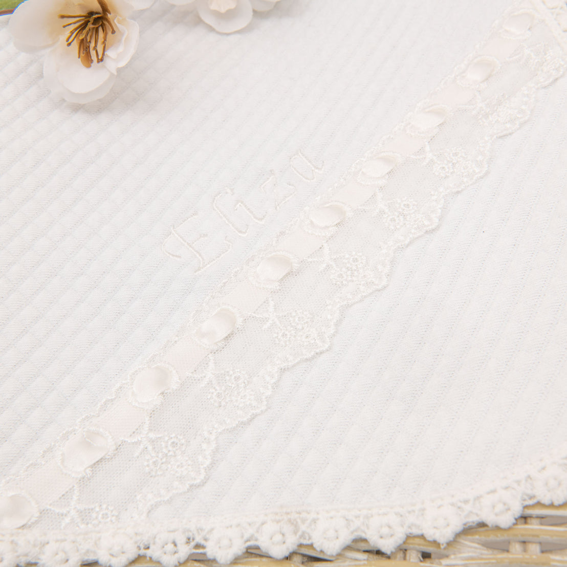 Close-up of a textured Eliza Personalized Blanket with an embroidered design and lace detailing, suitable for a baptism.