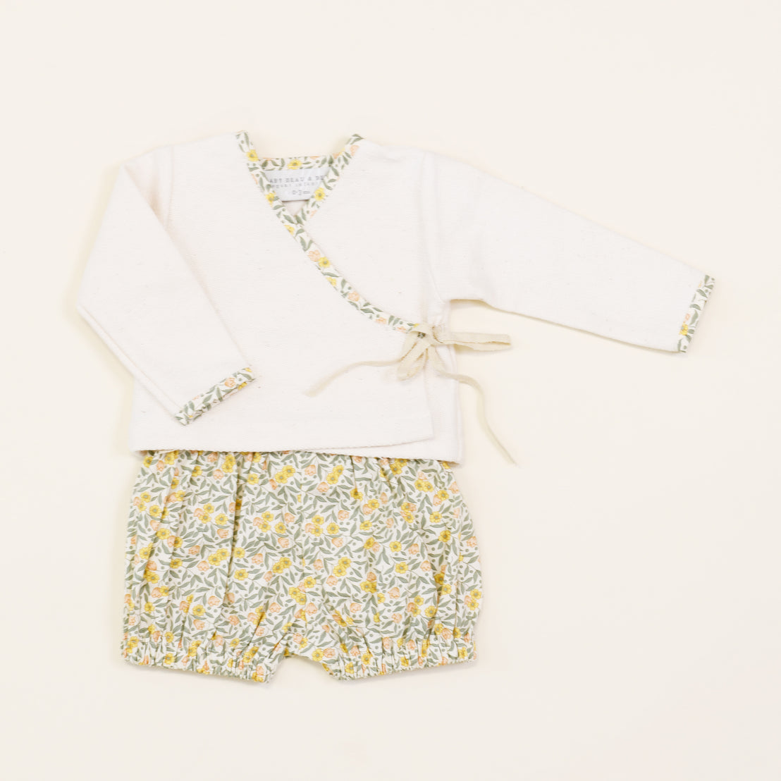 A Petite Fleur Wrap Top & Bloomers with vintage-inspired floral trim and matching floral shorts displayed on a plain background.