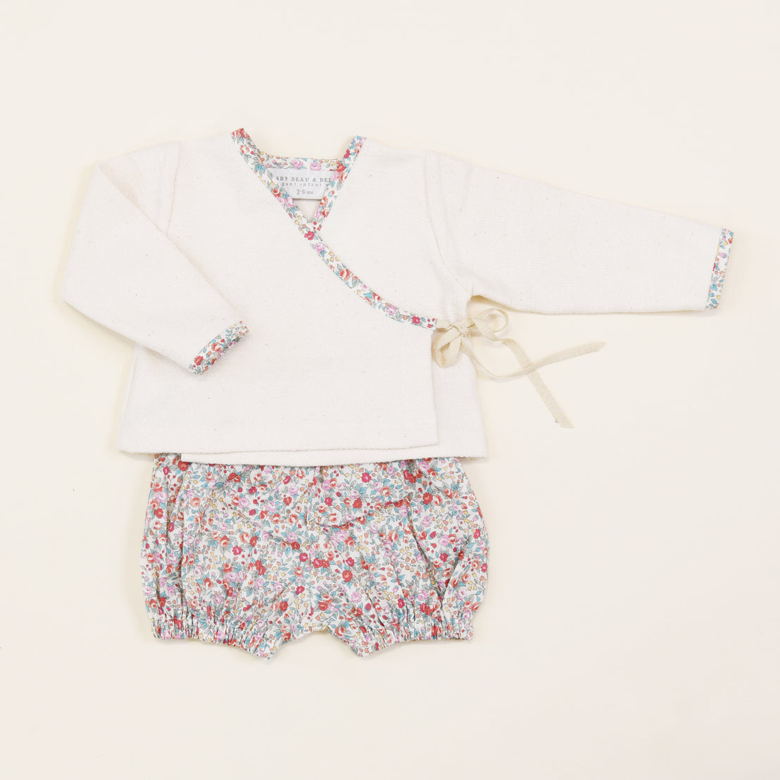 Petite Fleur Wrap Top & Bloomers baby heirloom kimono top with floral trim and matching floral shorts, laid flat on a light background.