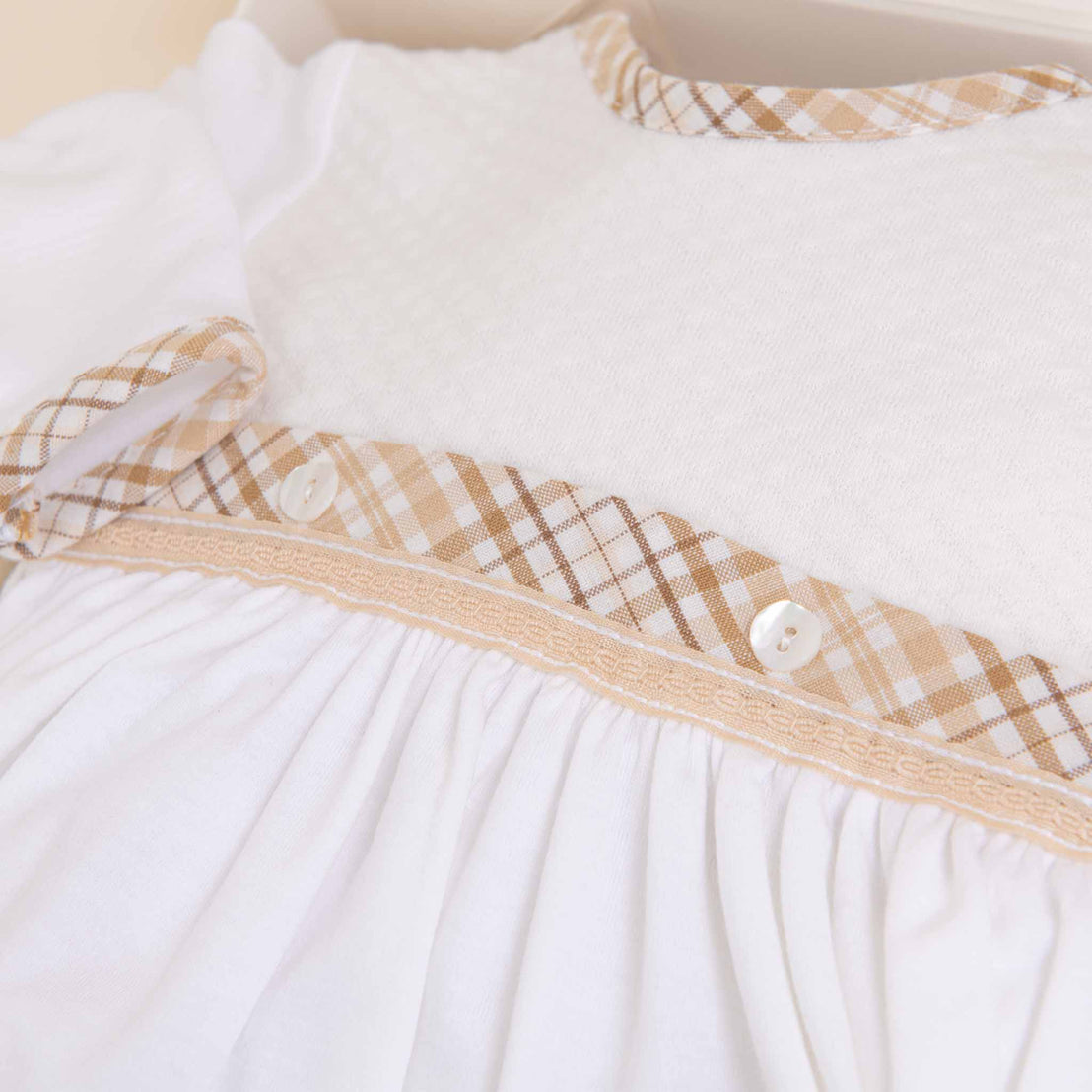 Close-up of a Dylan Newborn Gift Set with checkered beige trim and small buttons, featuring delicate lace detailing.