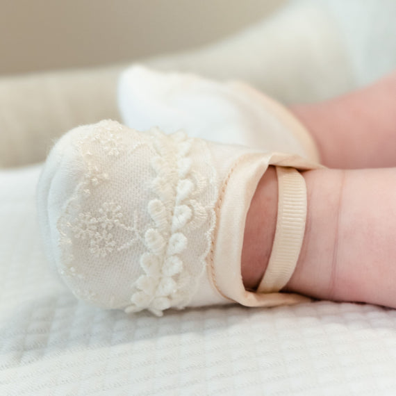 Baby girl wearing the Tessa Quilt Booties made from a soft textured cotton in white with an Ivory Edge Lace.