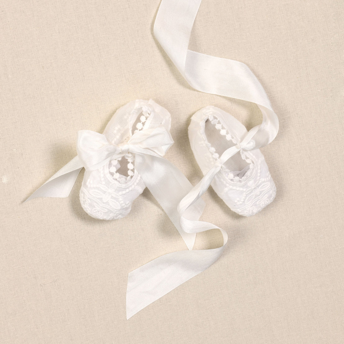 Flat lay photo of the Adeline baptism baby booties. Featuring long ribbon.