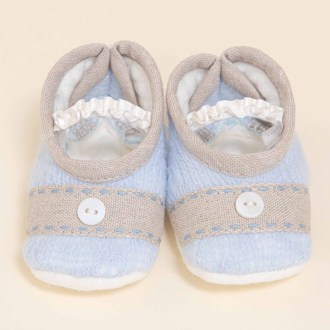 A pair of Austin Booties with blue tops and a white button on each, displayed on a light beige background.