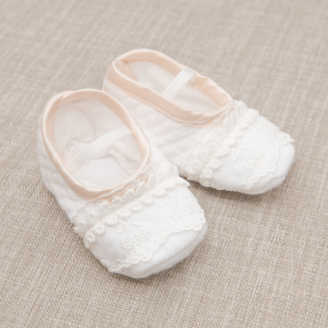 Flat lay photo of the Tessa Quilt Booties made from a soft textured cotton in white with an Ivory Edge Lace.