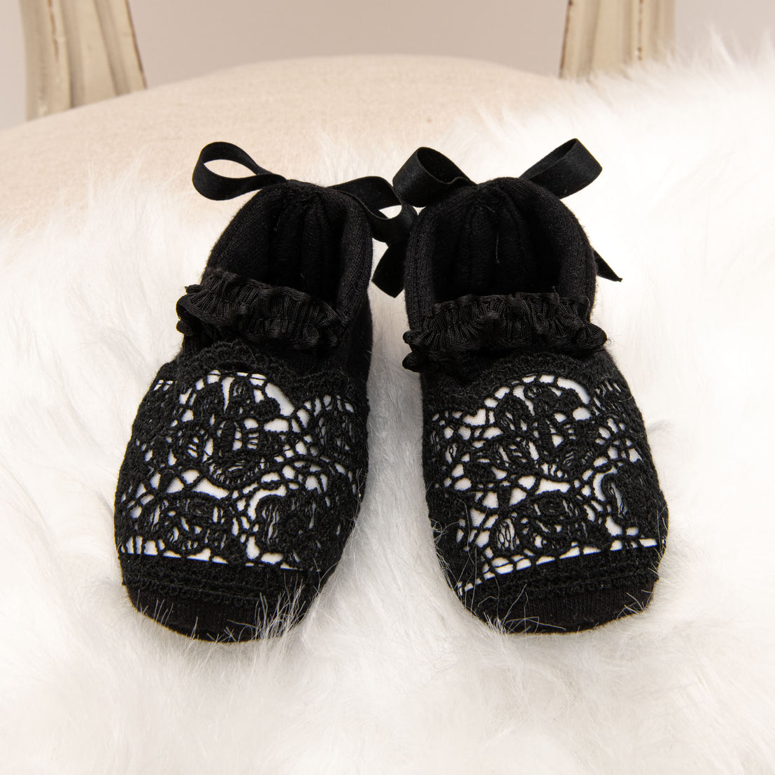 A pair of elegant June Booties with white satin ribbon ties, displayed on a fluffy white textured background.