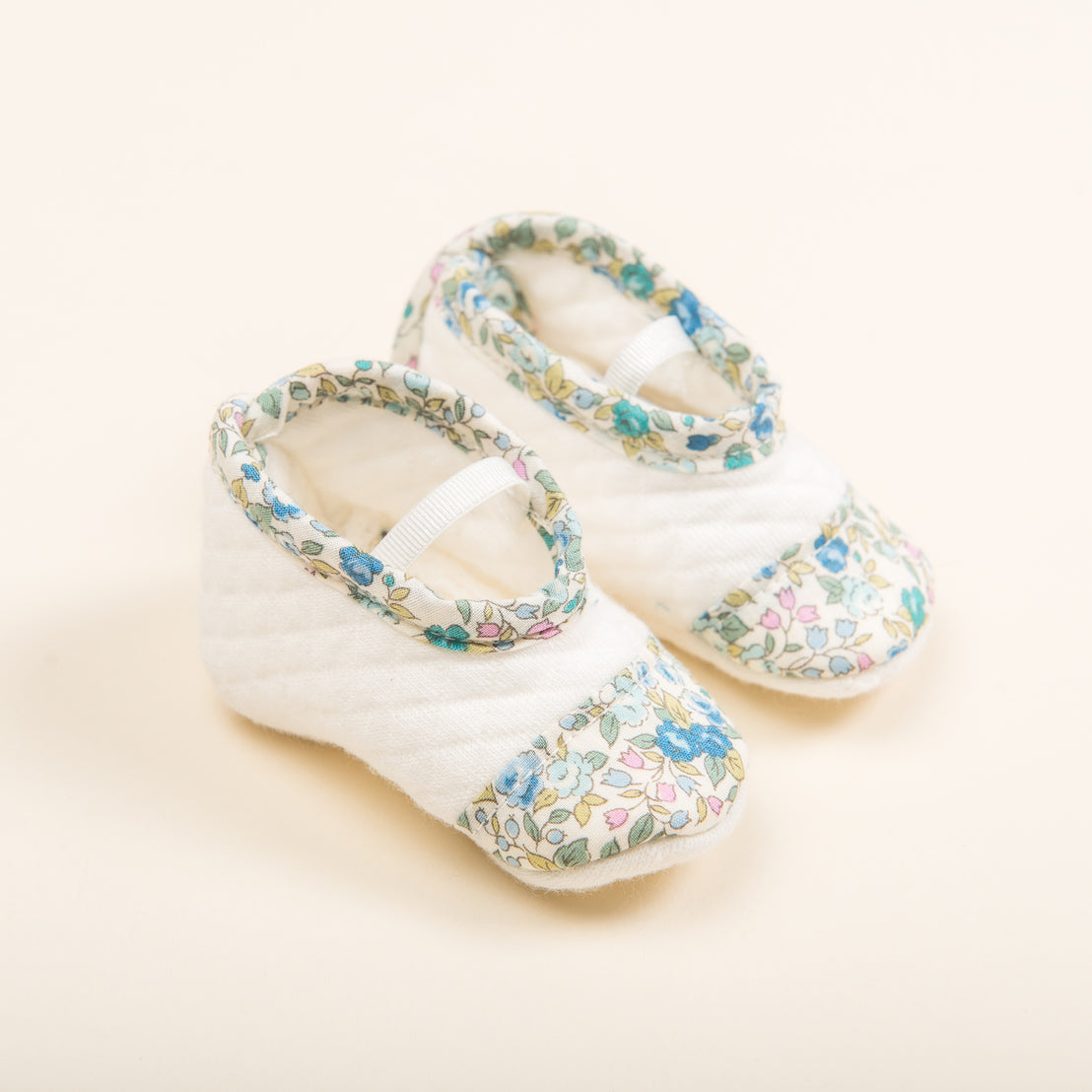 A pair of Petite Fleur Quilted Booties with white tops and floral patterned sides on a neutral background.