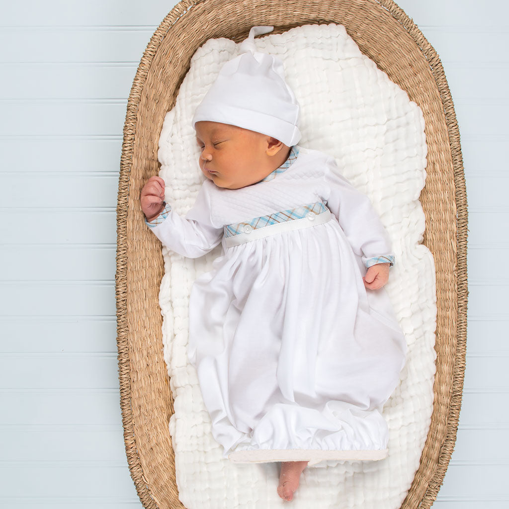 Newborn baby sleeping in a Mason Newborn Gift Set dressed in a white baptism gown and hat, with a light blue stripe and bow detail.