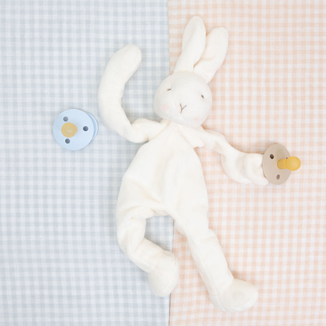 A vintage Isla Silly Bunny Buddy & Pacifier on a contrasting pastel checkered background appears soft and cuddly, ideal for infants. 