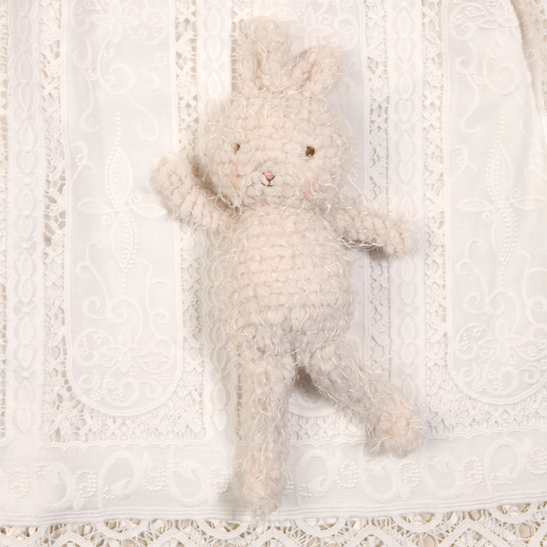 Flat lay photo of the Adeline plush bunny doll. Photographed atop the Adeline Baptism Gown. 