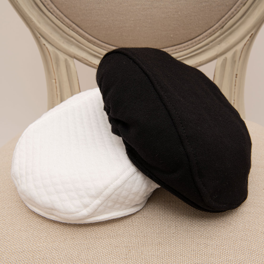 Flat lay photo of both the black and white James Newsboy Cap.