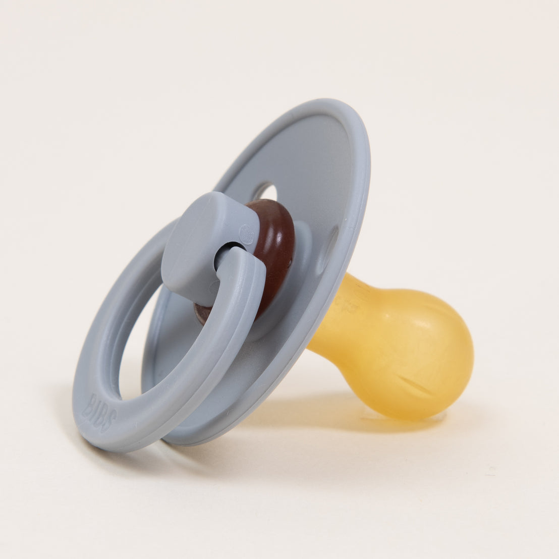 A Bibs Pacifier in Cloud with a yellow nipple, resting on a neutral background.