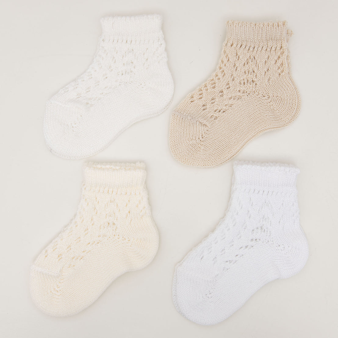 Four pairs of white Crochet Socks with different openwork patterns, displayed against a light background.