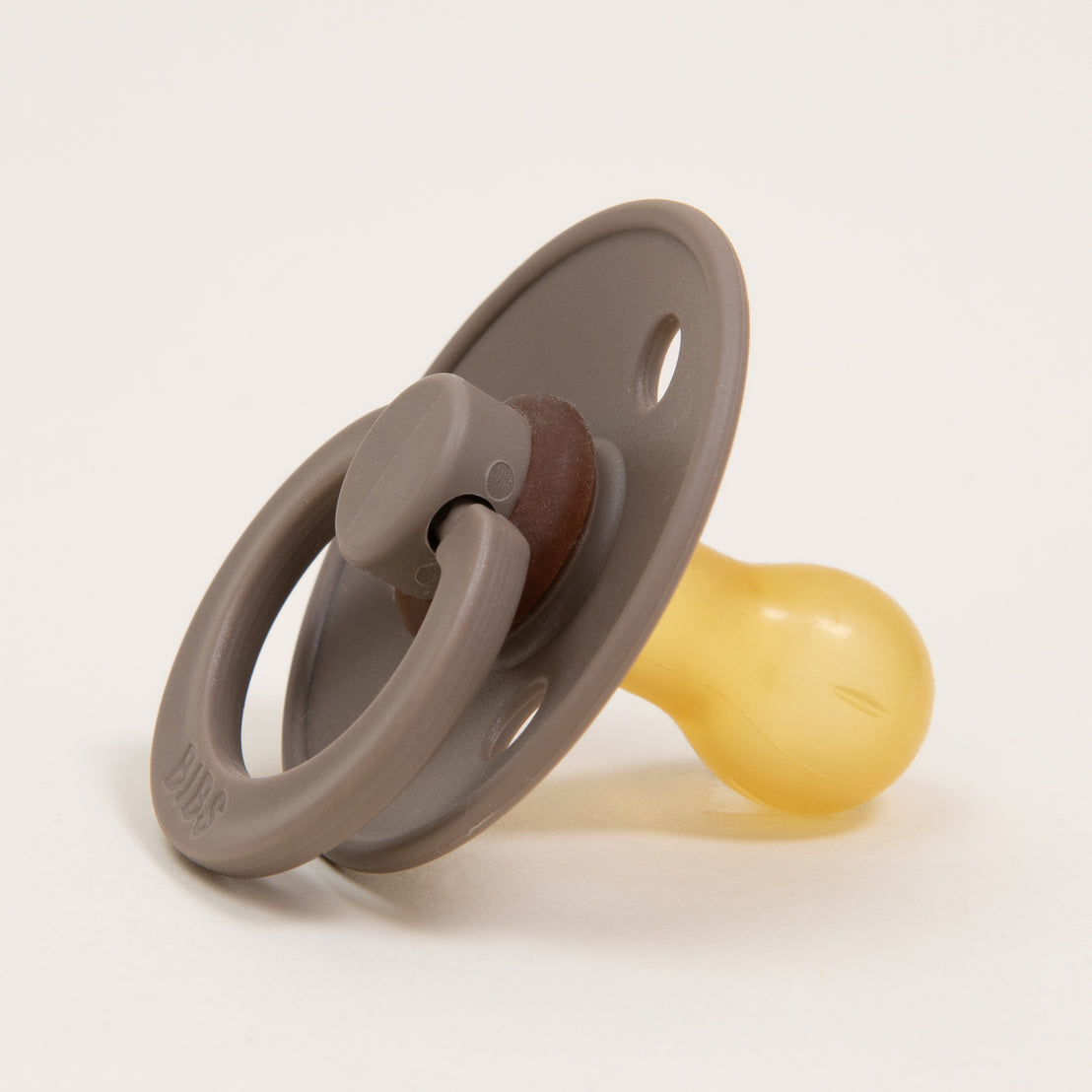 A dark oak Bibs pacifier with a natural rubber nipple and a handle, isolated on a light background.