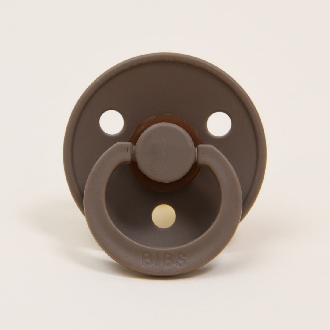 A Mason Pacifier in Dark Oak with a round shield and two ventilation holes, featuring a vintage heirloom design with the brand name "bibs" inscribed at the center front.