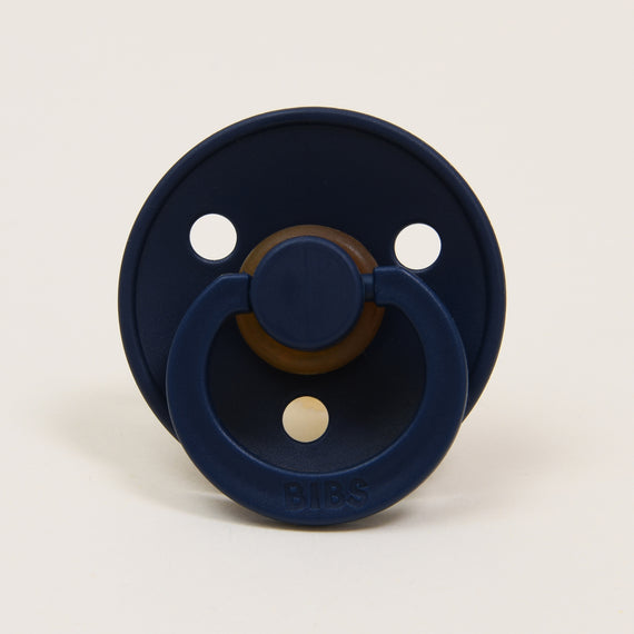 A deep space baby pacifier with a classic appearance, featuring a round shield and two large air holes, made with a natural rubber nipple and the brand name "Bibs" embossed at the front.