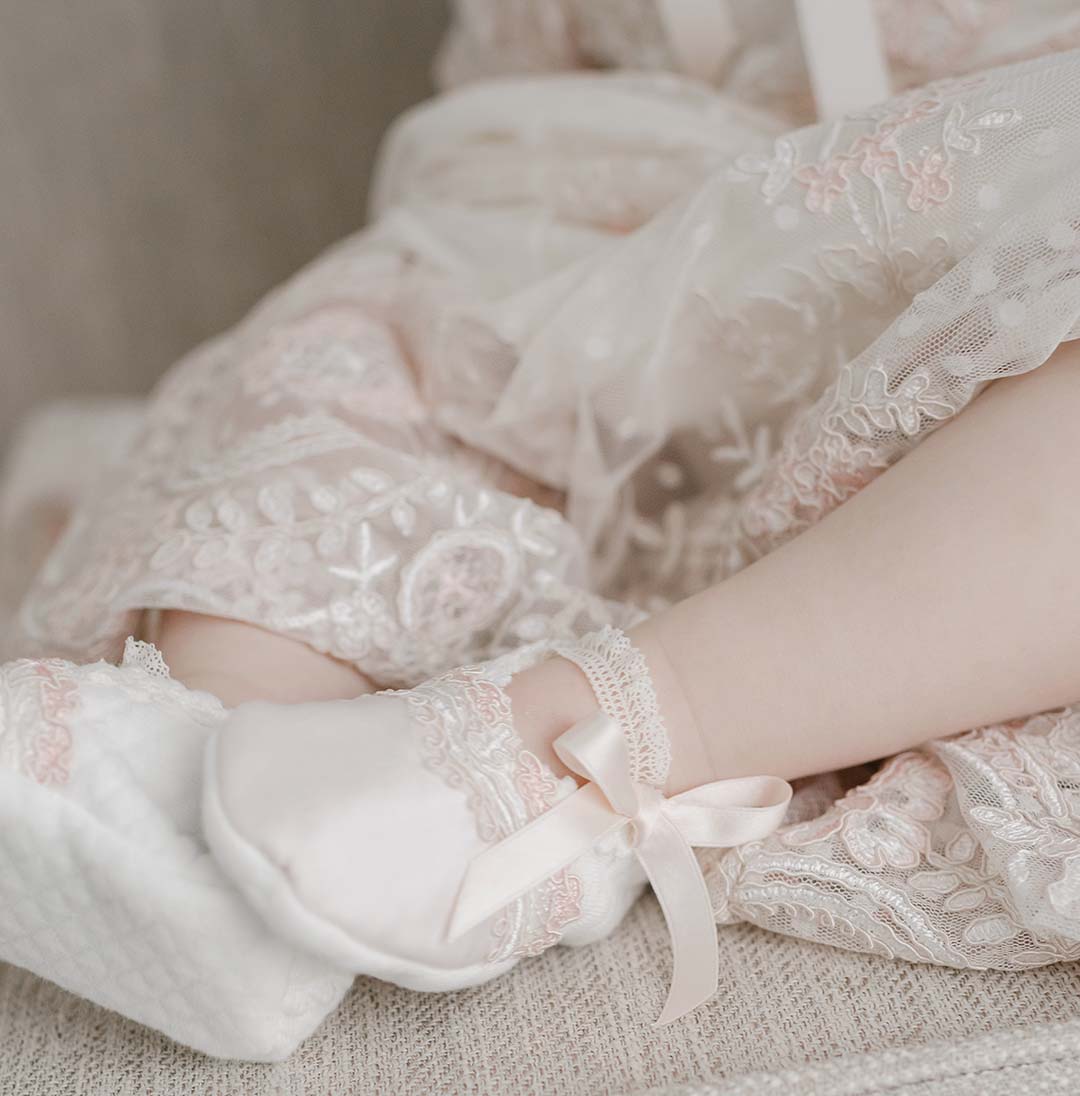 Close-up image of a small child's legs wearing Elizabeth Booties, draped in delicate vintage lace fabric.