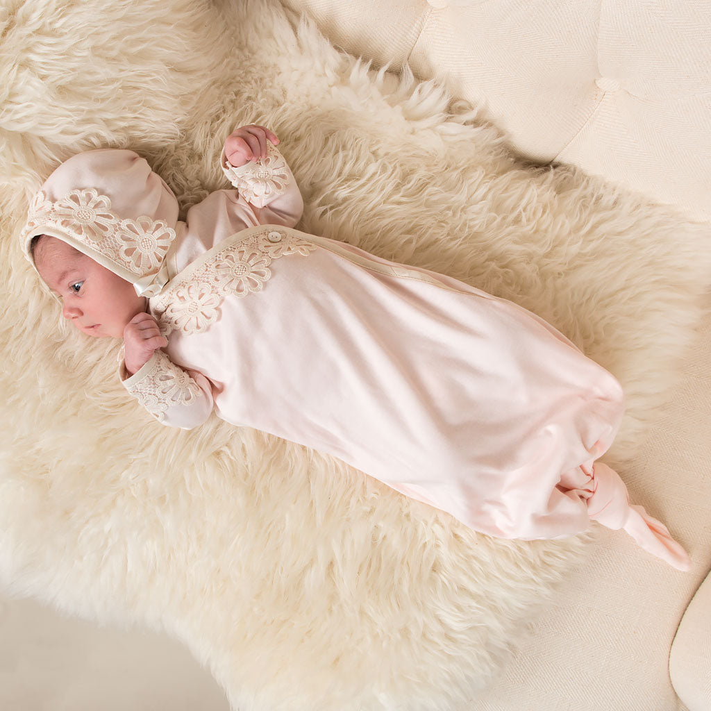A newborn baby in a Hannah Newborn Gift Set- Save 10% with lace details and a matching bonnet, part of a vintage baby clothes layette, lying on a fluffy white fur blanket.