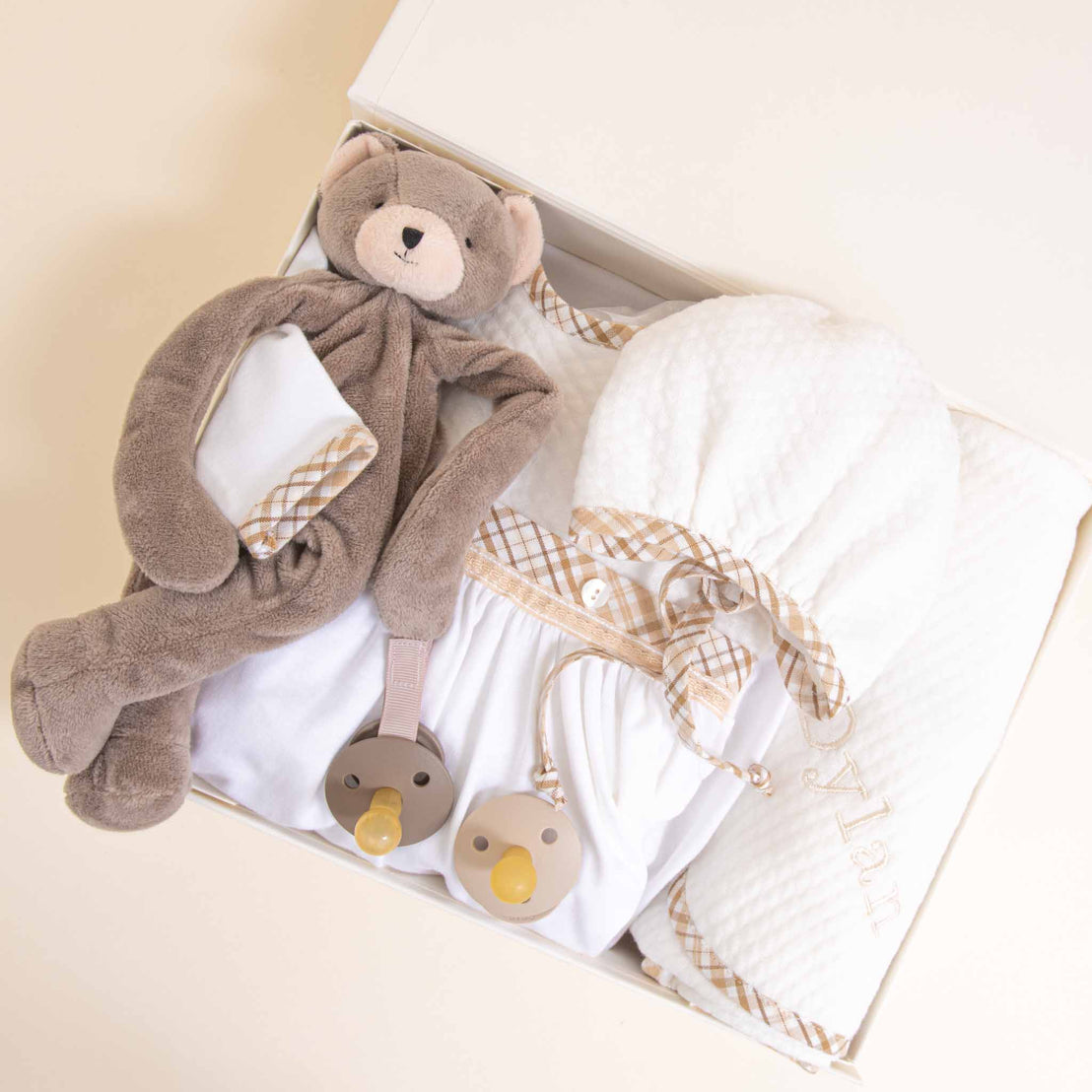 A baby gift box containing a Dylan Newborn Gift Set, all neatly arranged and displayed on a cream background.