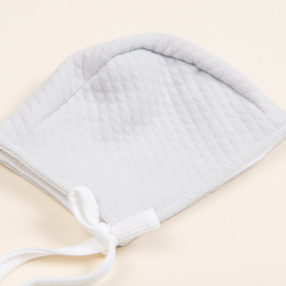 The Grayson baby boy bonnet made of super soft quilted cotton. Flat lay photo.