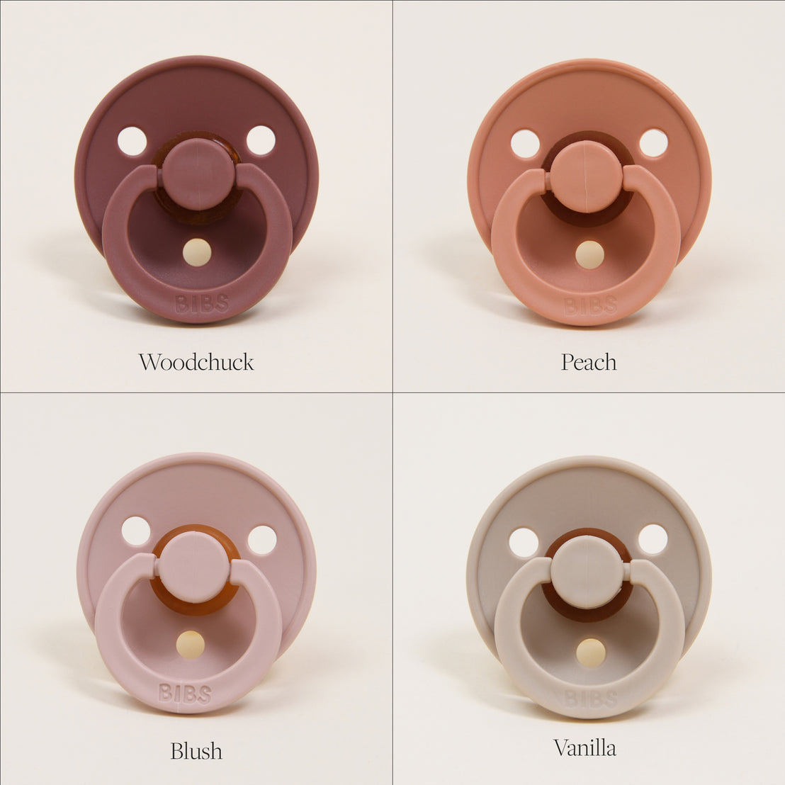 Four Bibs Pacifiers in colors labeled woodchuck, peach, blush, and vanilla against a cream background, arranged in a grid. Each pacifier has a round shield.