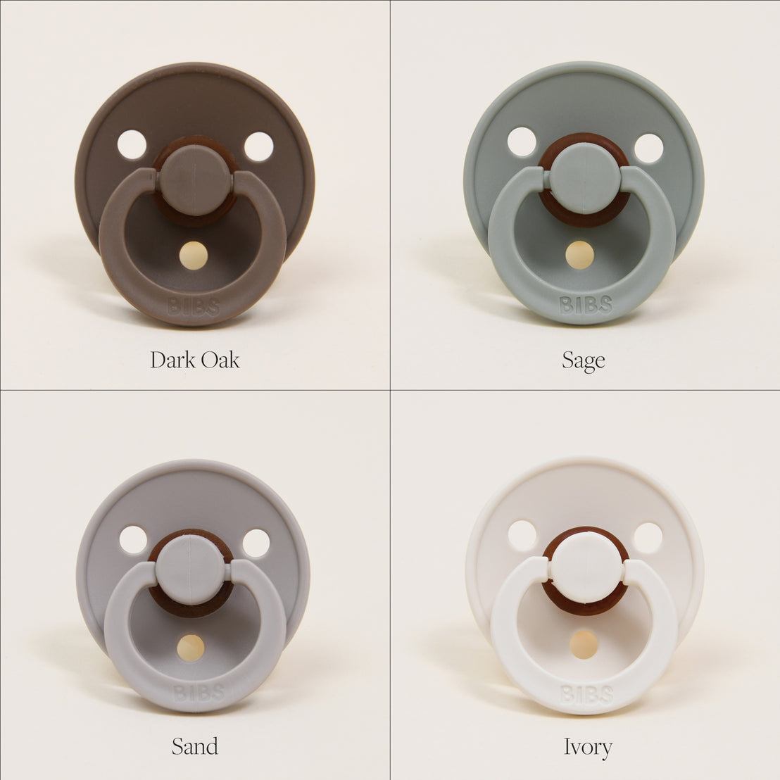 Four Bibs Pacifiers, designed in Denmark, in different colors labeled dark oak, sage, sand, and ivory, each displayed against a plain cream background.